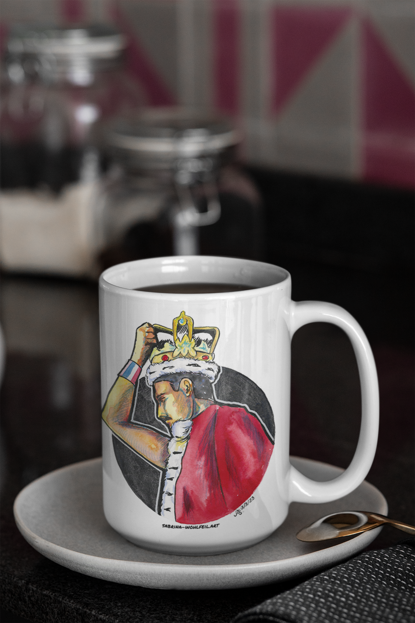 Weiße Keramiktasse mit Freddie Mercury Fanart-Print in Bühnenoutfit mit Krone auf grauem Tisch. BPA-frei, glänzend, in zwei Größen.