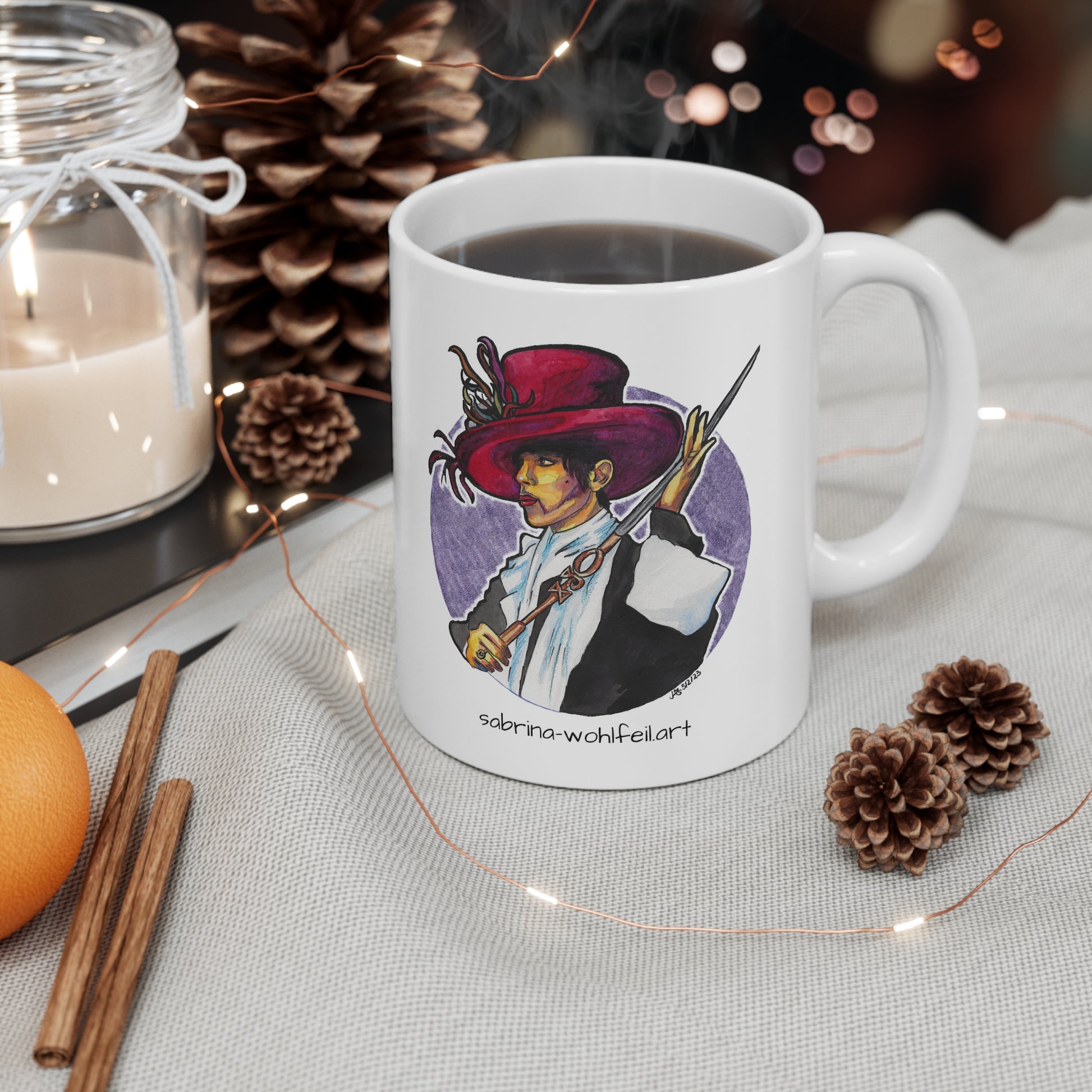 Weiße Keramiktasse mit Aquarell-Porträt des Musikers Prince in ikonischem Outfit, neben Kerzen und Weihnachtsdekoration.