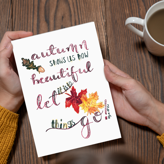 Postkarte in Kunstdruck Qualität mit Handlettering Motiv "Let Things Go" und herbstlichen Blättern, gehalten von Händen mit Tee auf Holztisch