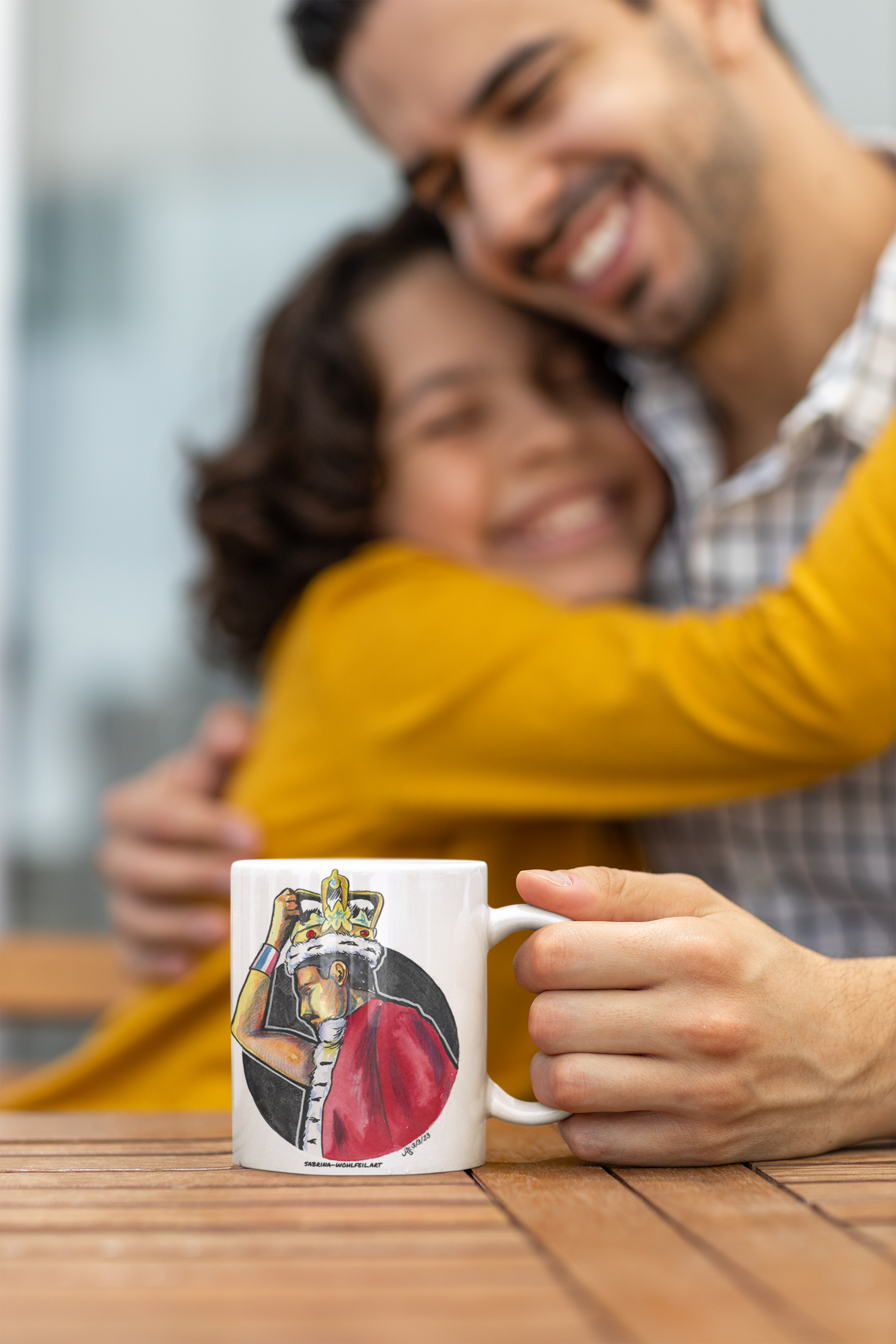 Vater und Tochter umarmen sich, halten weiße Keramiktasse mit Fanart-Print von Freddie Mercury in Bühnenoutfit und Krone, perfekt für Queen-Fans