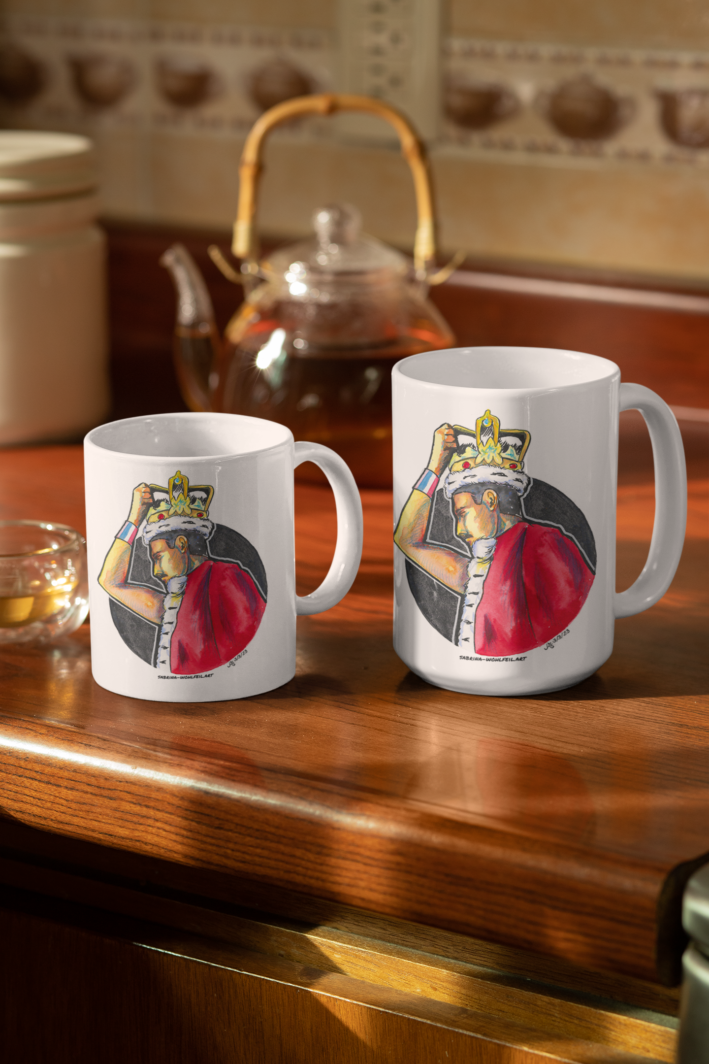 Zwei weiße Keramiktassen mit Freddie Mercury Fanart-Print und glossy Finish in 330 ml und 440 ml, auf einer Küchenarbeitsplatte.